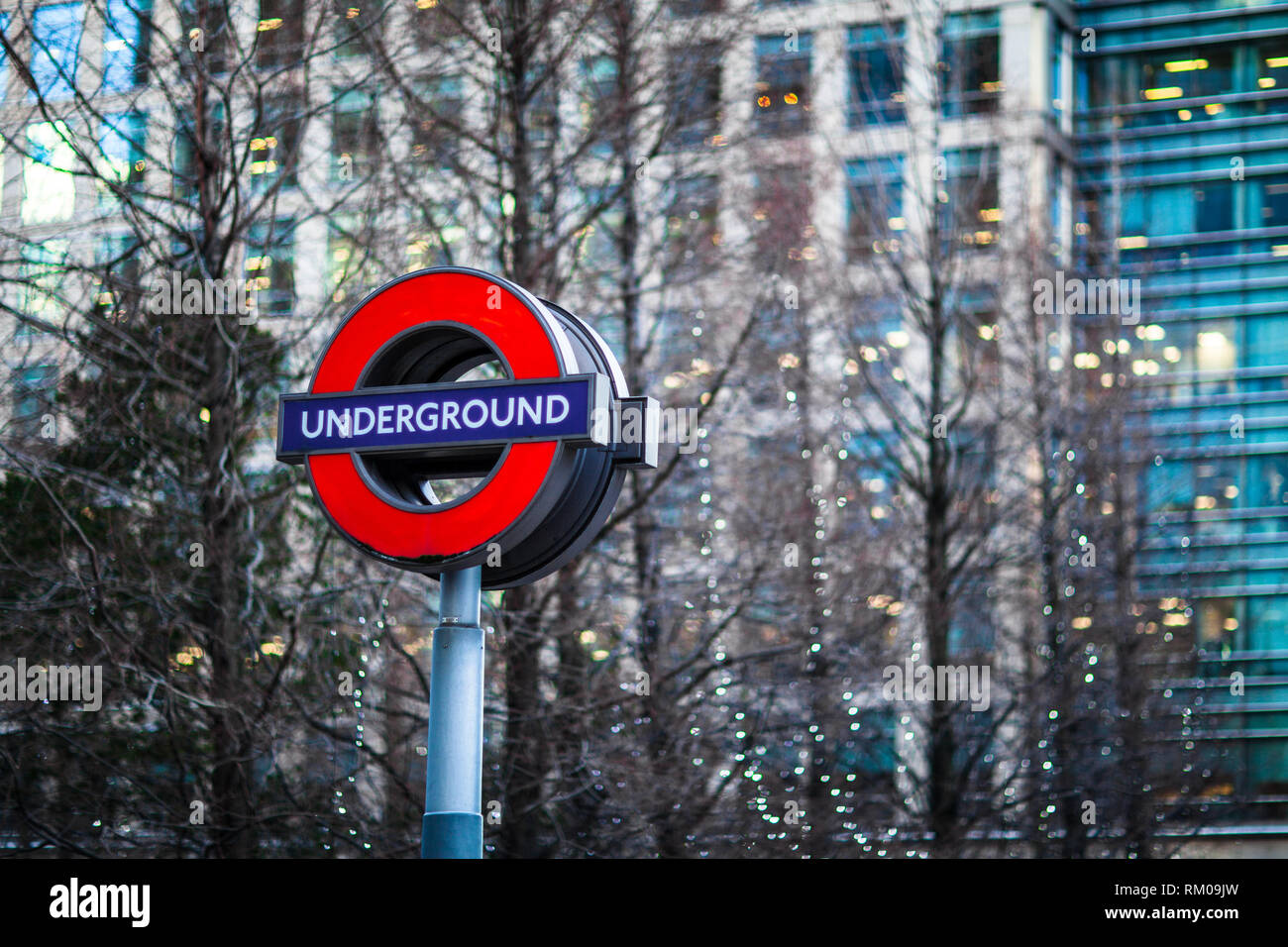 Canary Wharf London Underground segno contro le luci e gli edifici di Canary Wharf a Londra est Foto Stock