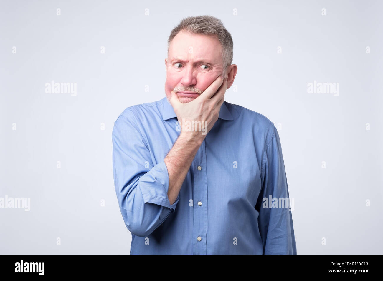 Senior Uomo in camicia blu a pensare la sua pensione Foto Stock