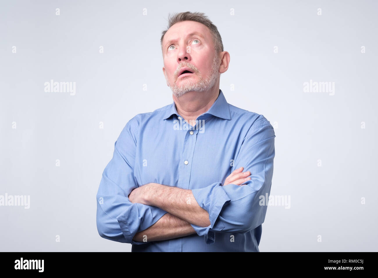 Senior Uomo in camicia blu rolling gli occhi. Foto Stock