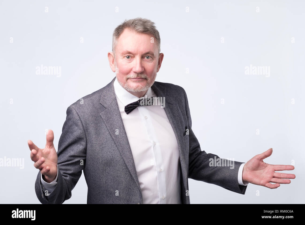 Senior business man studio isolato in piedi sul muro grigio mani a parte Foto Stock