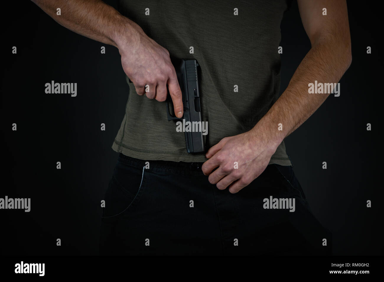 L'uomo cerca di nascondere la sua pistola sotto il suo pantaloni Foto Stock
