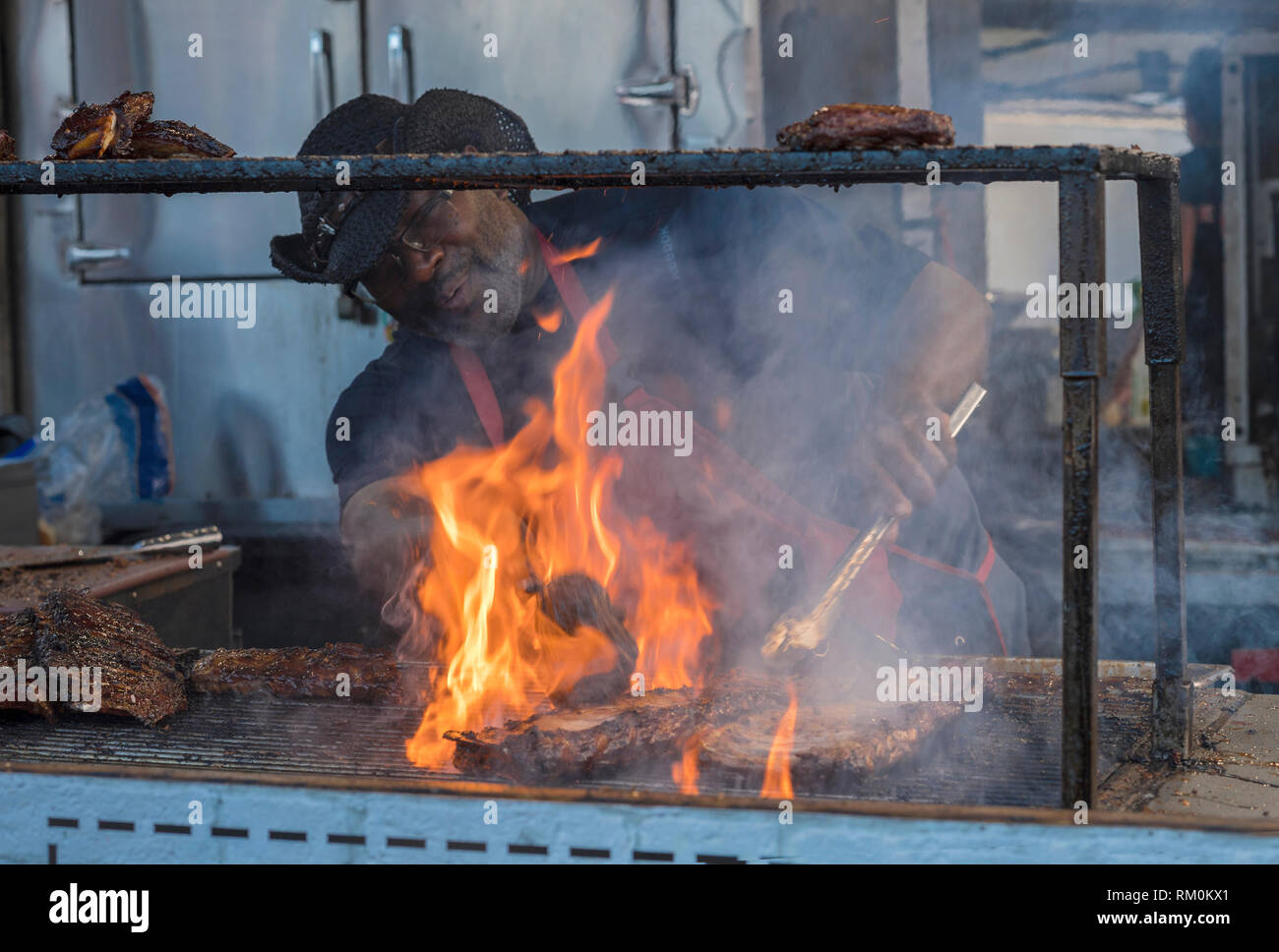 Uomo bistecche di cottura su un barbecue con le fiamme e il fumo. Foto Stock