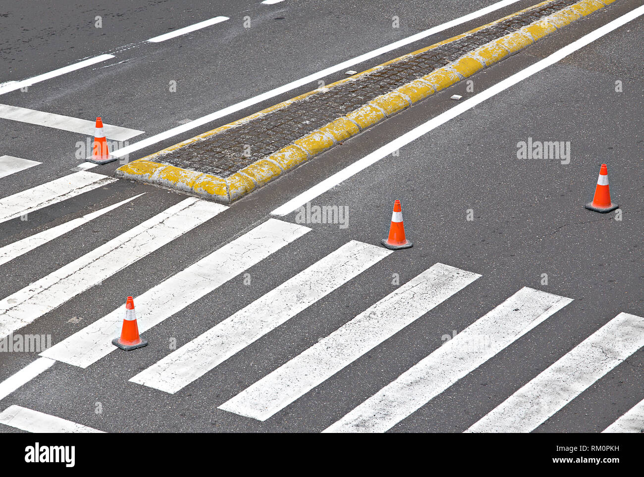 La strada dipinta con linee bianche, crosswalk e striato coni arancione Foto Stock