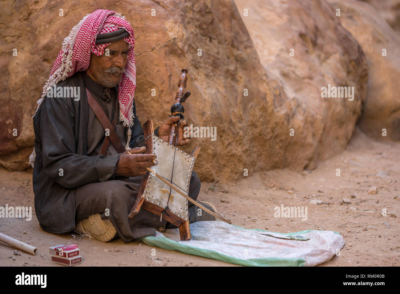 Bedouin uomo gioca un rebab in uno sperone di wadi vicino a Petra in Giordania. Foto Stock