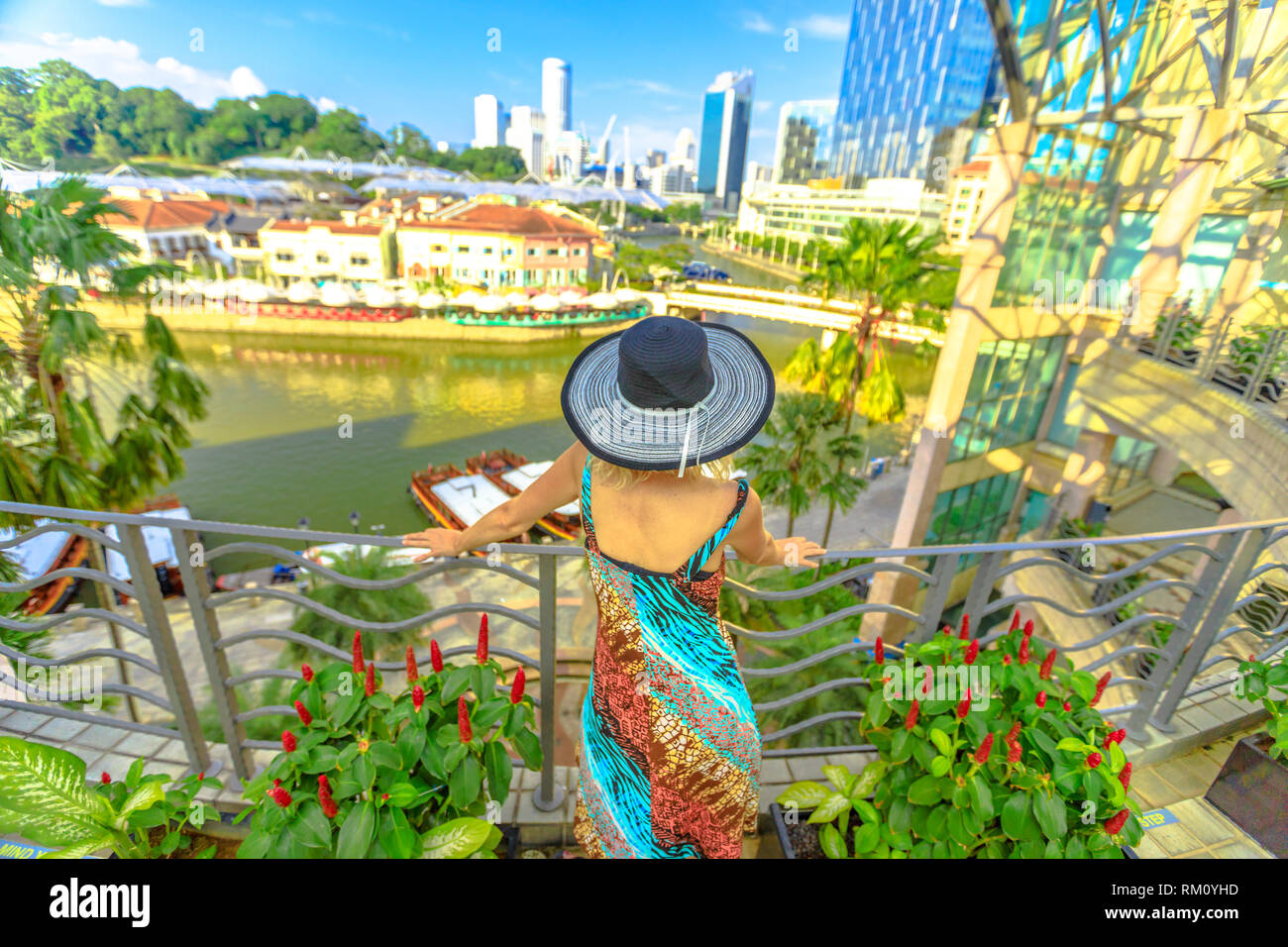 Donna turistica con ampia hat cerca panorama dalla terrazza su Clarke Quay e area lungo il fiume di Singapore, Sud-est asiatico.Crociera sul Fiume Singapore Foto Stock