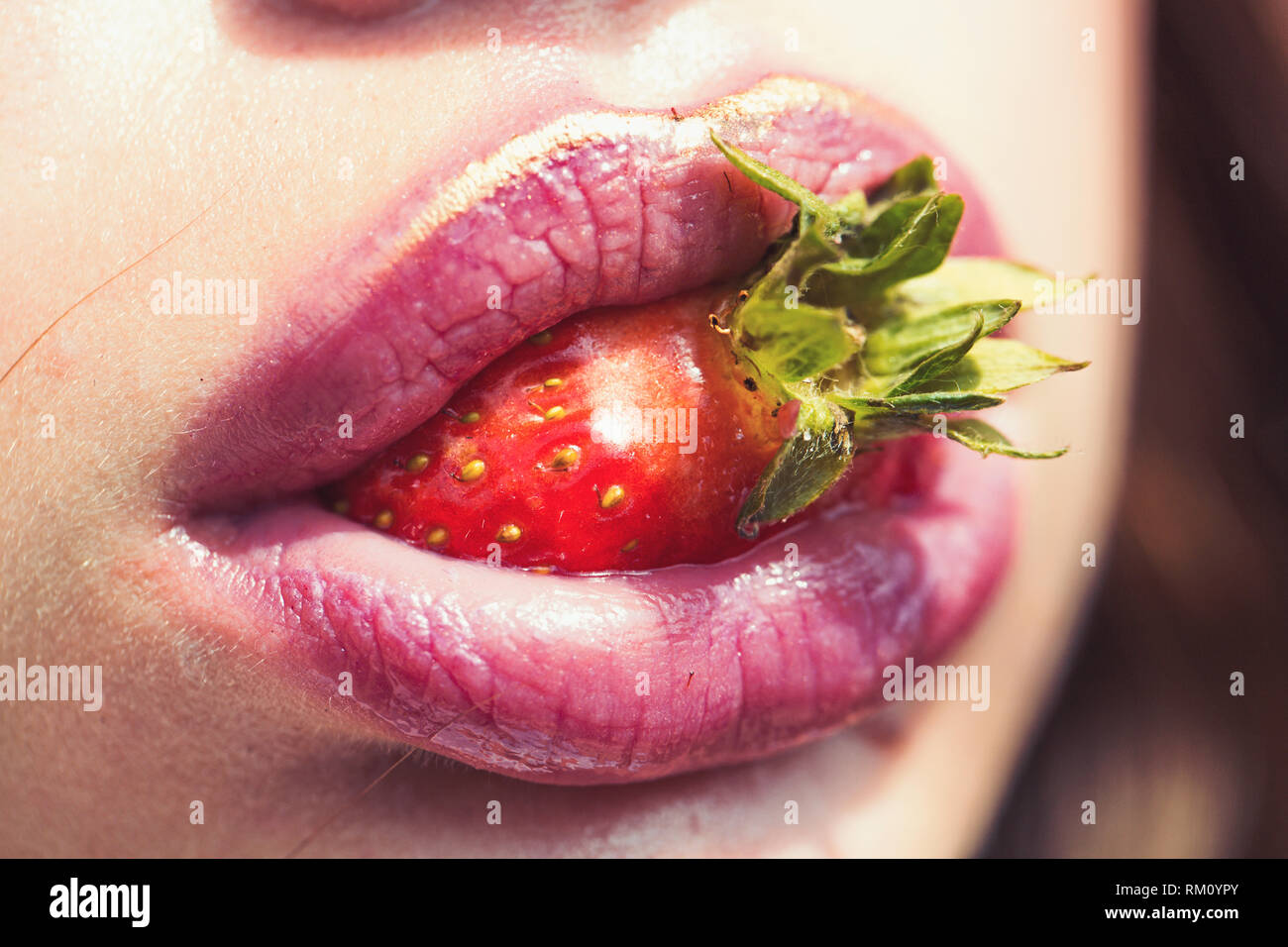 Fragola in bocca con labbra rosate, trucco Foto stock - Alamy
