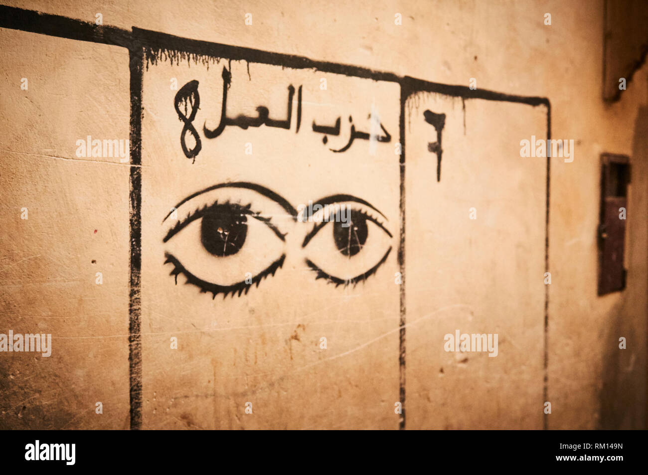 Un graffitied set di occhi femmina, la calligrafia Islamica e i numeri 7 e 8 all'interno di caselle dipinte dipinta su un muro di Fez, Marocco. Foto Stock