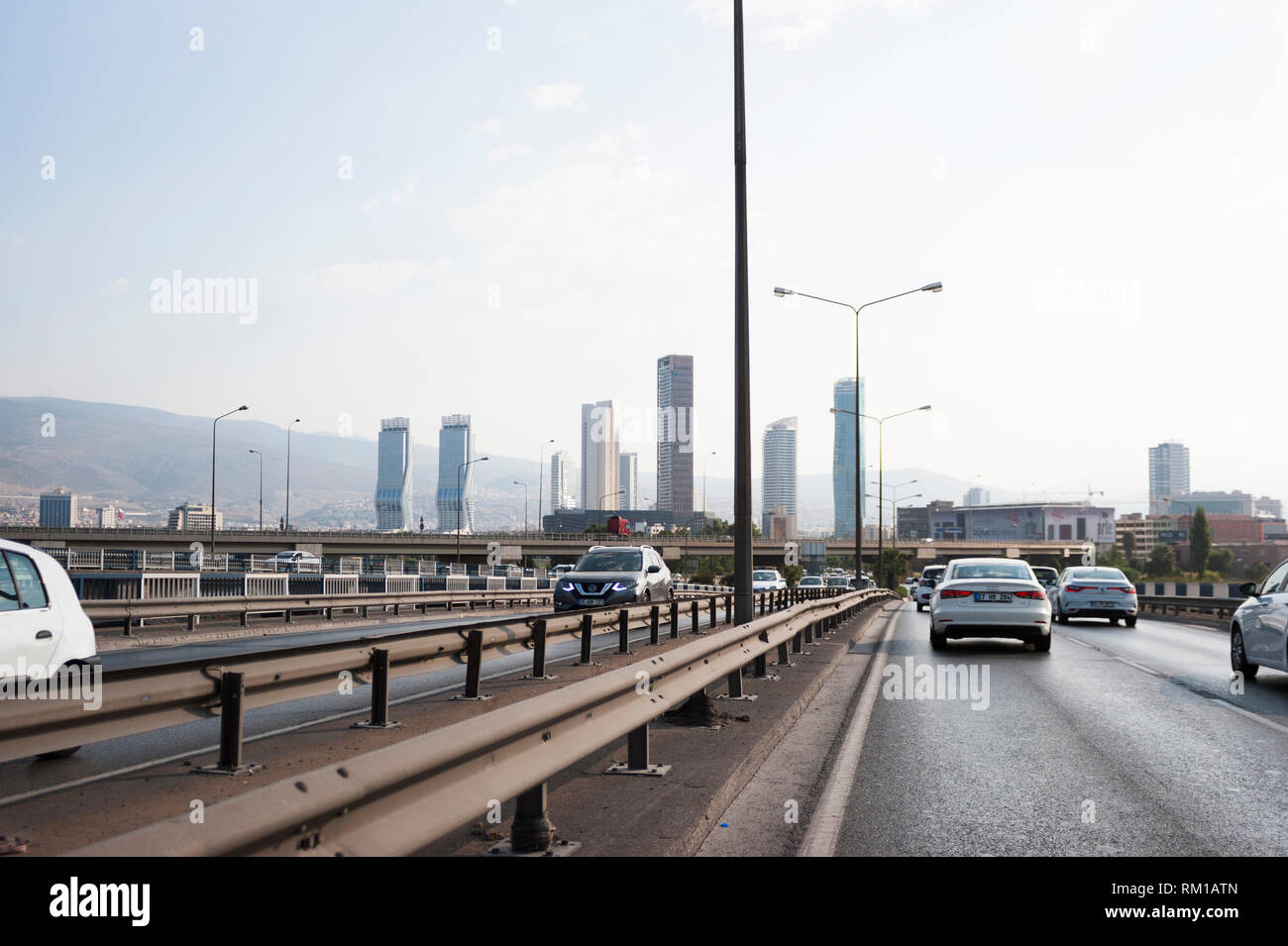 Izmir, Turchia - 8 Agosto 2018: Gee perla skyscrapper, Mistral skyscrapper e torri Folkart vista dalla strada di Ankara con il traffico di Izmir, Turchia. Foto Stock