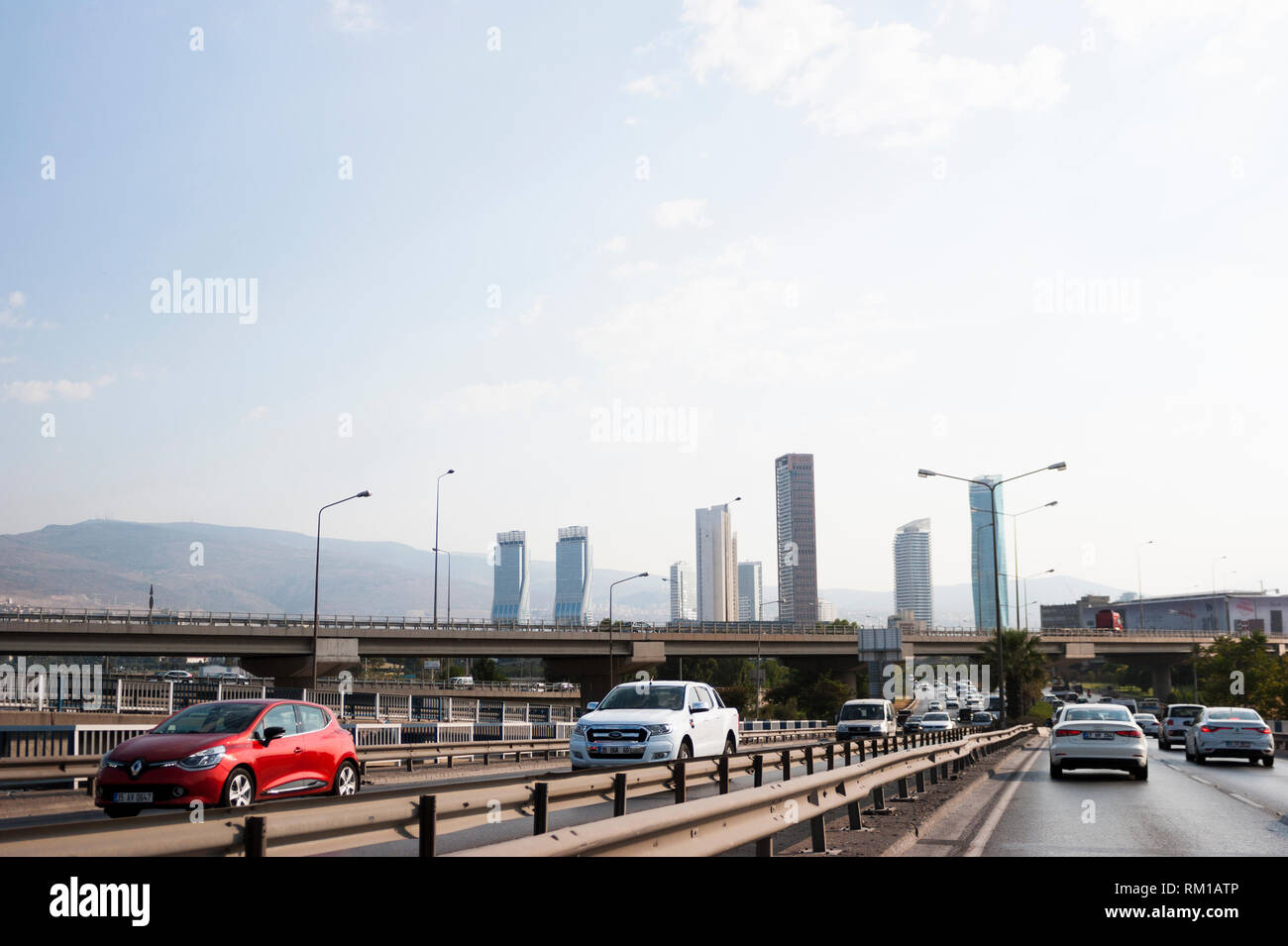 Izmir, Turchia - 8 Agosto 2018: Gee perla skyscrapper, Mistral skyscrapper e torri Folkart vista dalla strada di Ankara con il traffico di Izmir, Turchia. Foto Stock