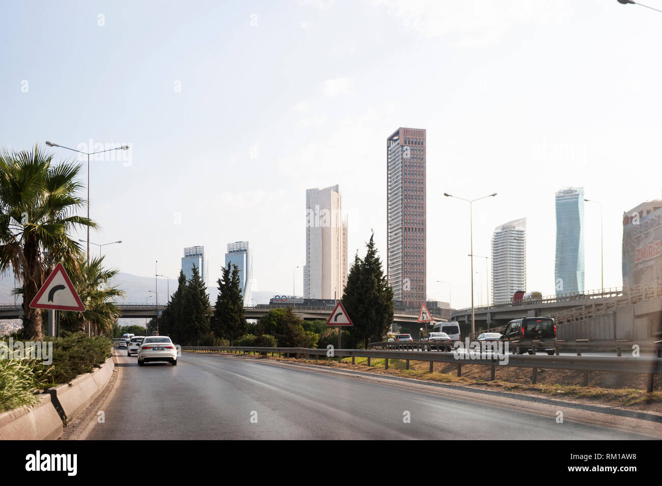 Izmir, Turchia - 8 Agosto 2018: Gee perla skyscrapper, Mistral skyscrapper e torri Folkart vista dalla strada di Ankara con il traffico di Izmir, Turchia. Foto Stock