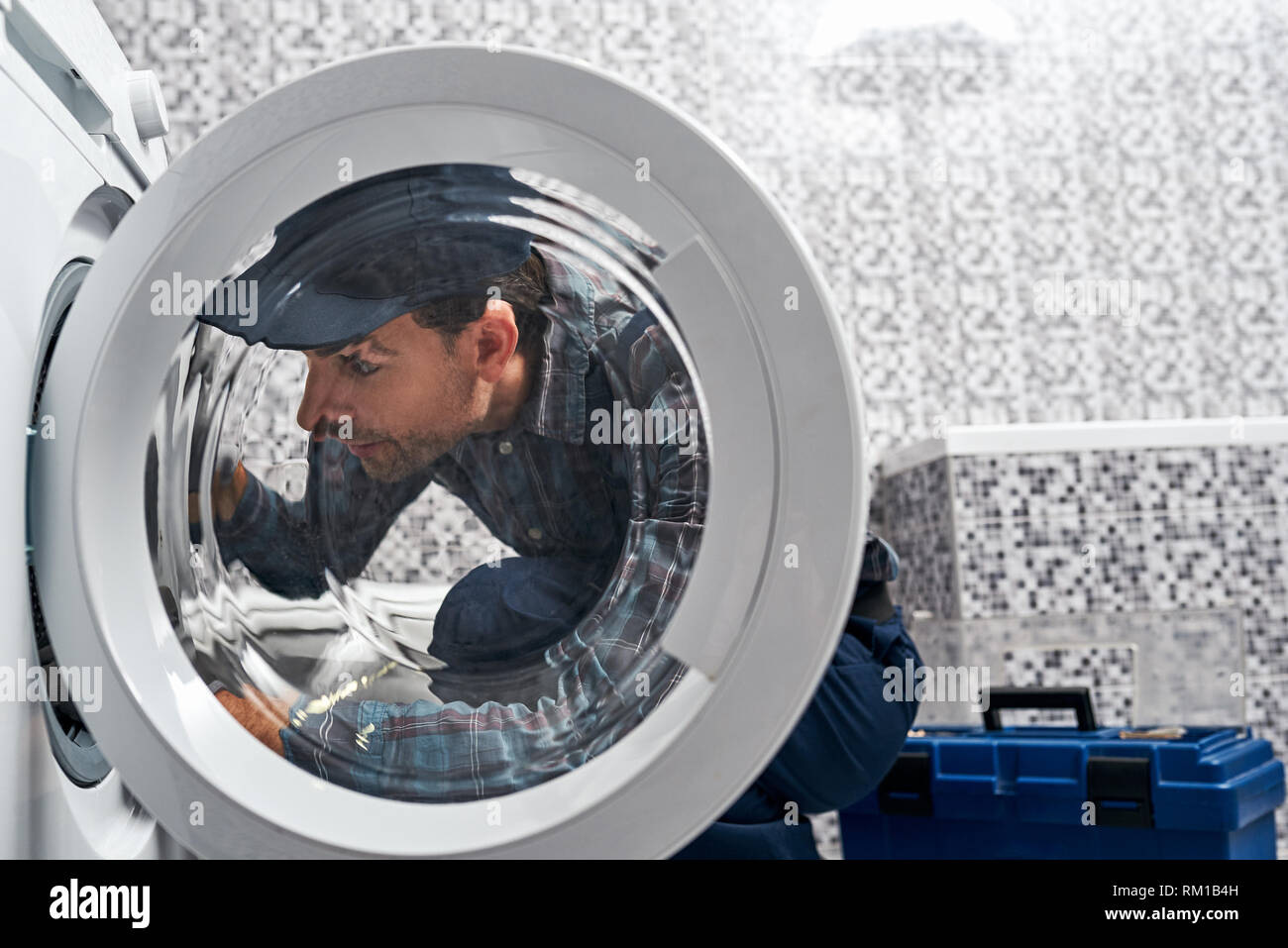 È facile. Uomo di lavoro idraulico in bagno il controllo del lavoro di wacher mashine di close-up Foto Stock