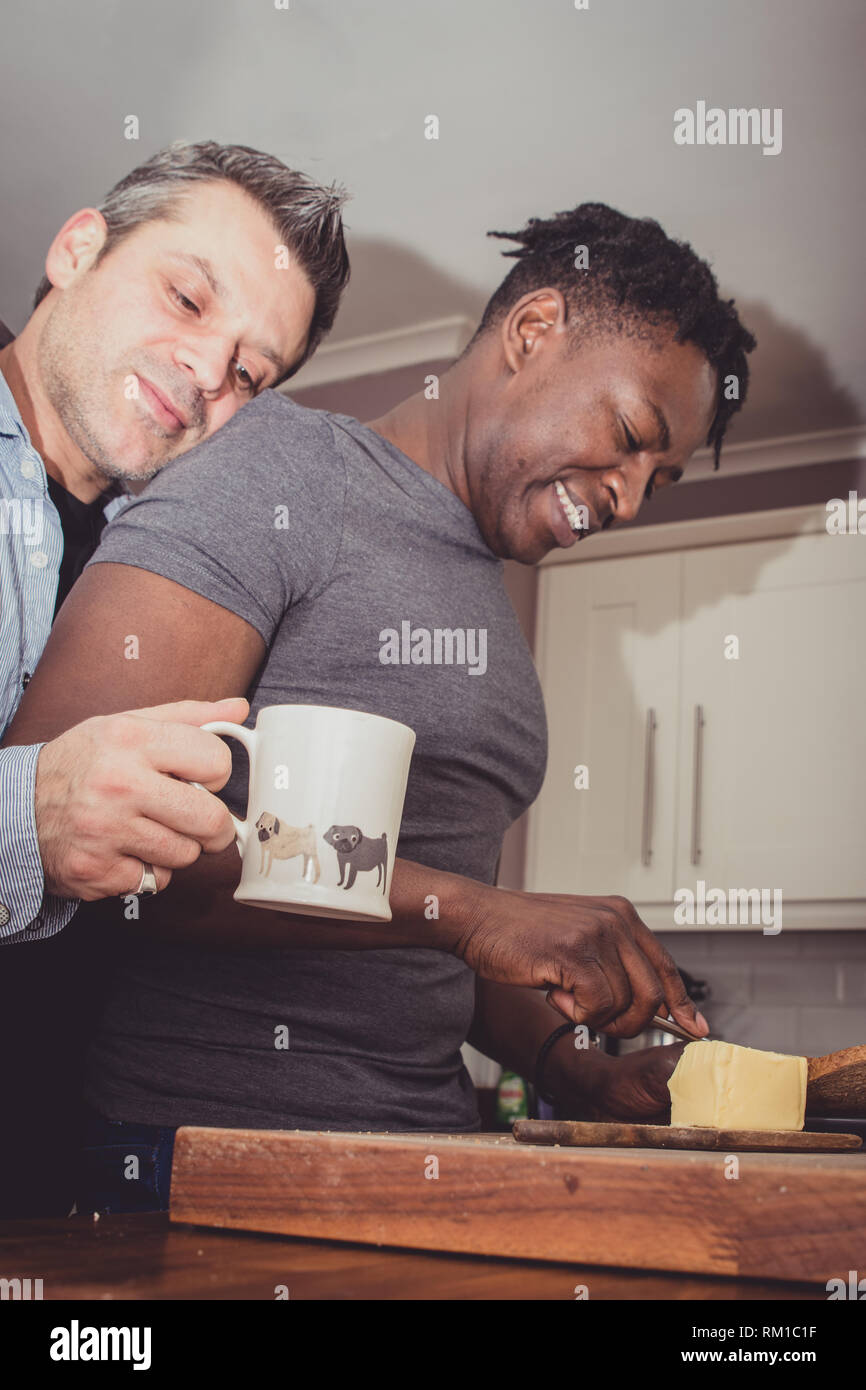 Una coppia gay condividendo storie dal loro giornata di lavoro su una fetta di pane tostato e una tazza di tè e caffè in serata. Foto Stock