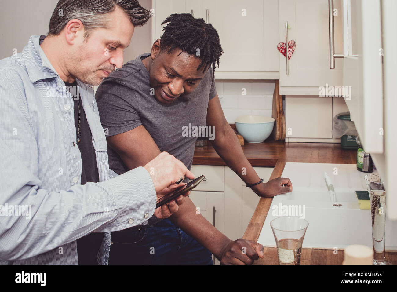 Una coppia gay condividendo storie dal loro giornata di lavoro su una fetta di pane tostato e una tazza di tè e caffè in serata. Foto Stock