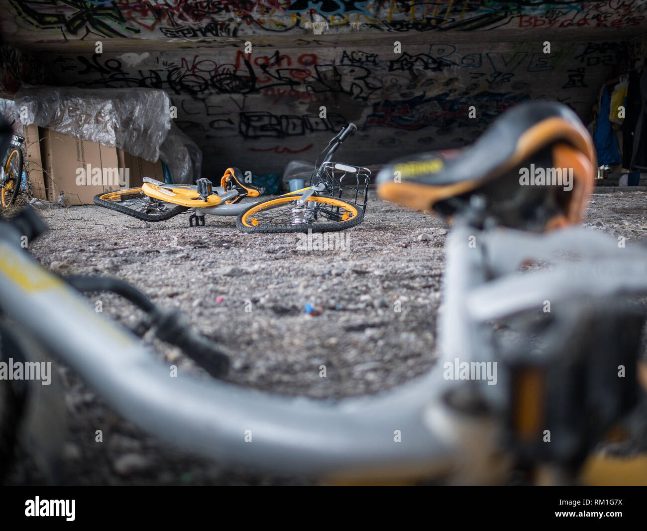 Vecchio rottame giallo biciclette sotto il cemento scale con graffiti e senzatetto rifugio del sonno Foto Stock Vecchio rottame giallo biciclette sotto il cemento scale con graffiti e senzatetto rifugio del sonno Foto Stock