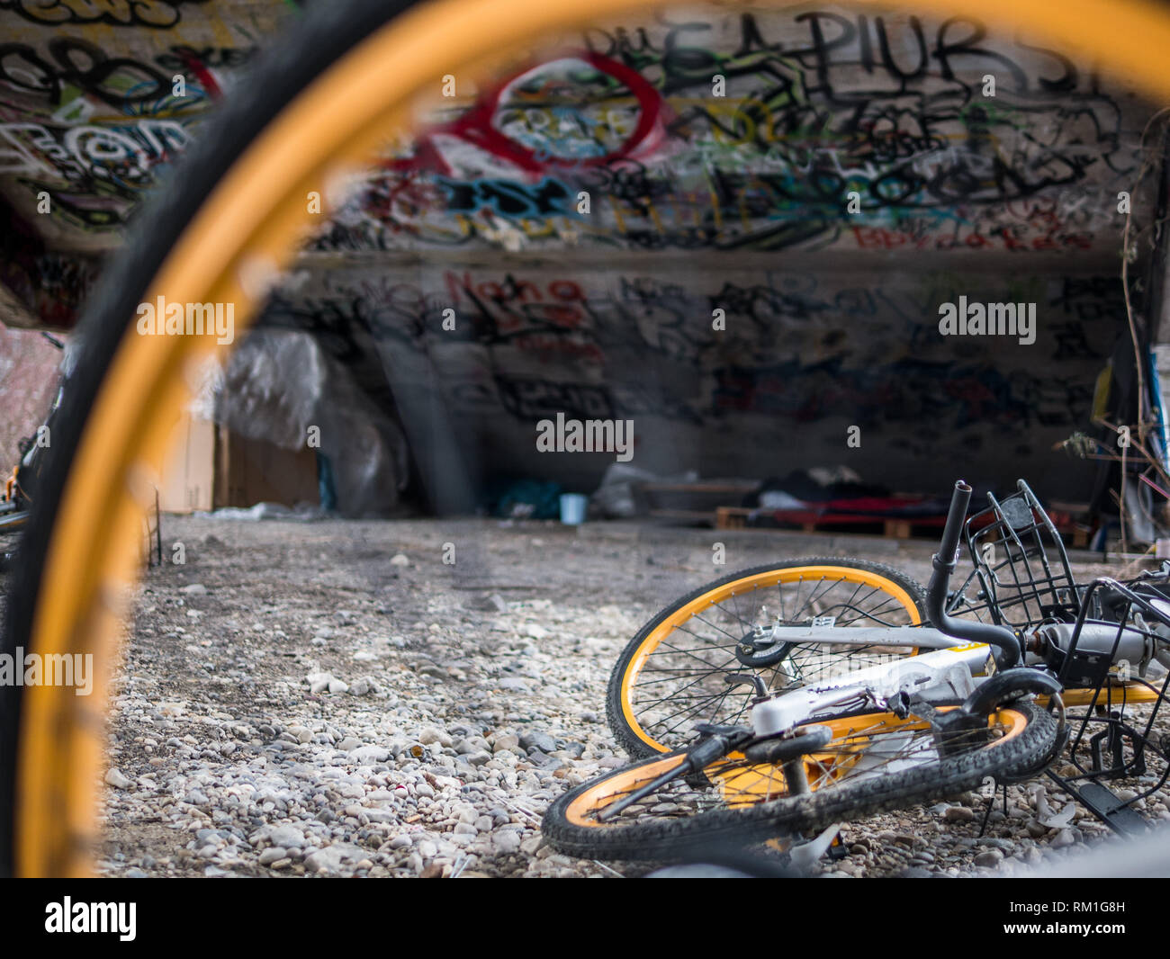 Vecchio rottame giallo biciclette sotto il cemento scale con graffiti e senzatetto rifugio del sonno Foto Stock