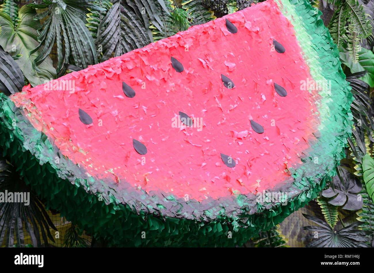 Modello di tropicale con la giungla di foglie e frutti di anguria sfondo floreale. Anguria in plastica con strato di foglie di palma Foto Stock