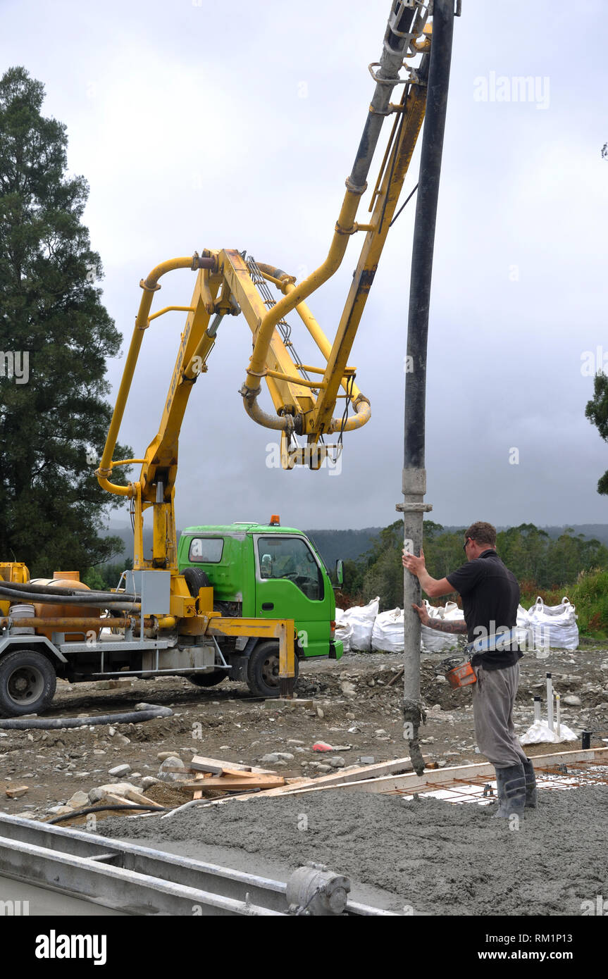 Builder utilizza una pompa per calcestruzzo per dirigere il calcestruzzo bagnato in le fondamenta di un edificio di grandi dimensioni Foto Stock