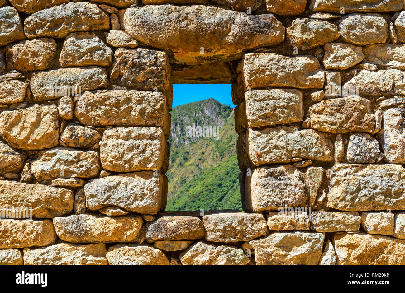 Parete Inca con finestra che si affaccia sulla foresta tropicale e la cordigliera delle Ande in Machu Picchu, Perù. Foto Stock