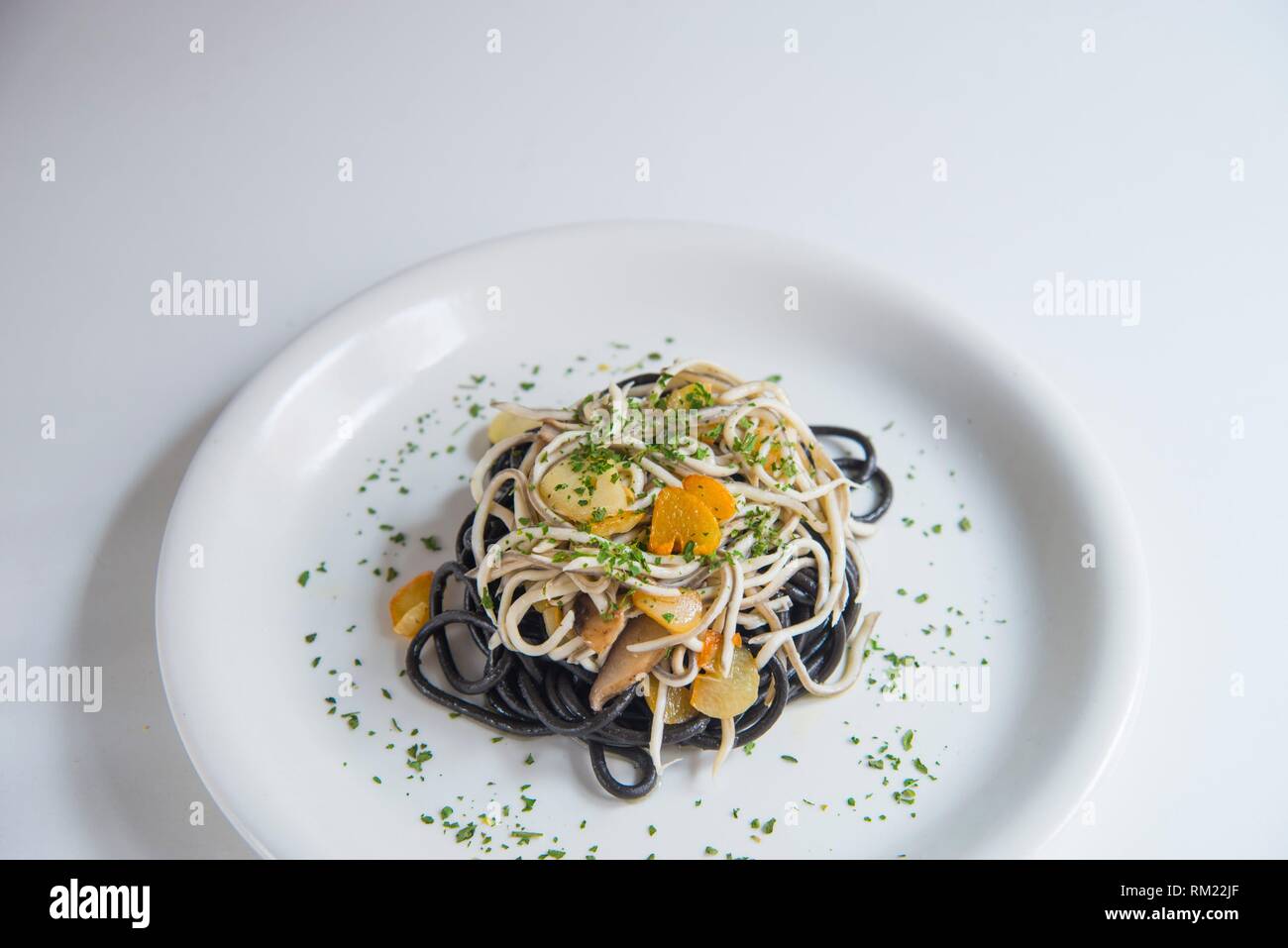 Gli spaghetti al nero di anguille, funghi, aglio e prezzemolo. Foto Stock