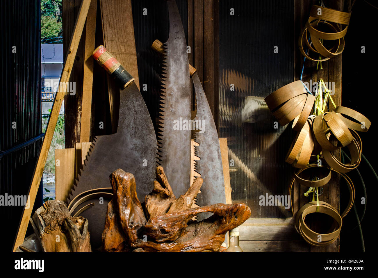 Grandi seghe, radica di legno e varie attrezzature per la lavorazione del legno nella parte anteriore di un vecchio negozio nel villaggio di Umaji, prefettura di Kochi, Shikoku Giappone Foto Stock