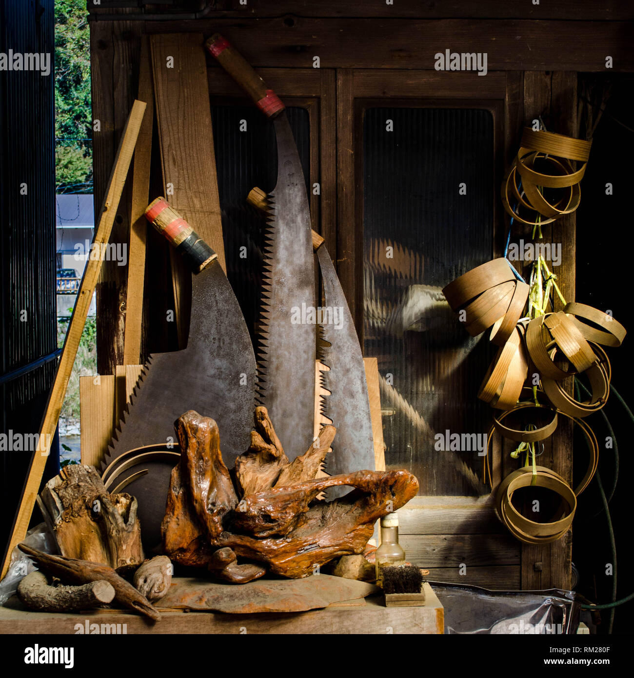 Grandi seghe, radica di legno e varie attrezzature per la lavorazione del legno nella parte anteriore di un vecchio negozio nel villaggio di Umaji, prefettura di Kochi, Shikoku Giappone Foto Stock