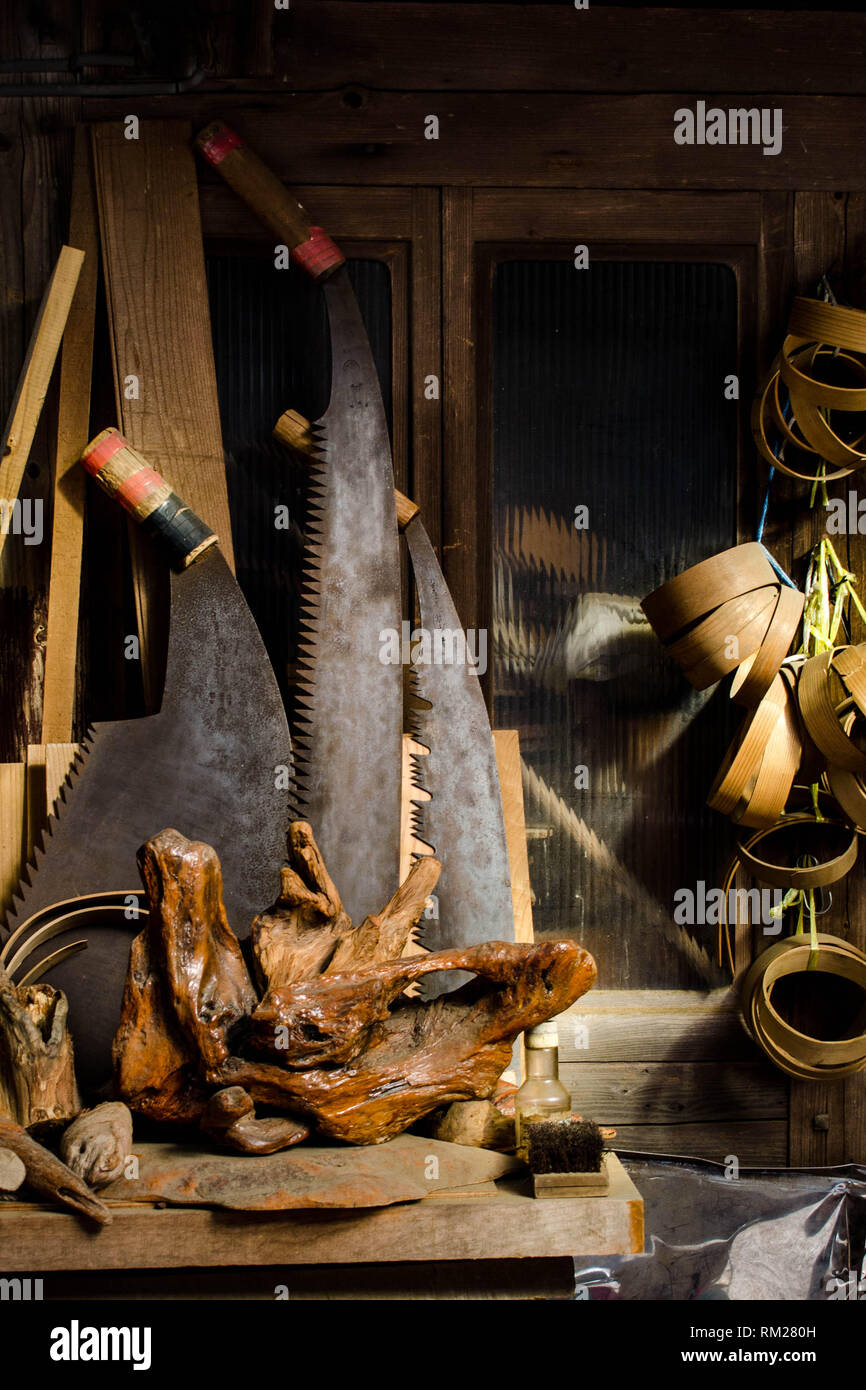 Grandi seghe, radica di legno e varie attrezzature per la lavorazione del legno nella parte anteriore di un vecchio negozio nel villaggio di Umaji, prefettura di Kochi, Shikoku Giappone Foto Stock