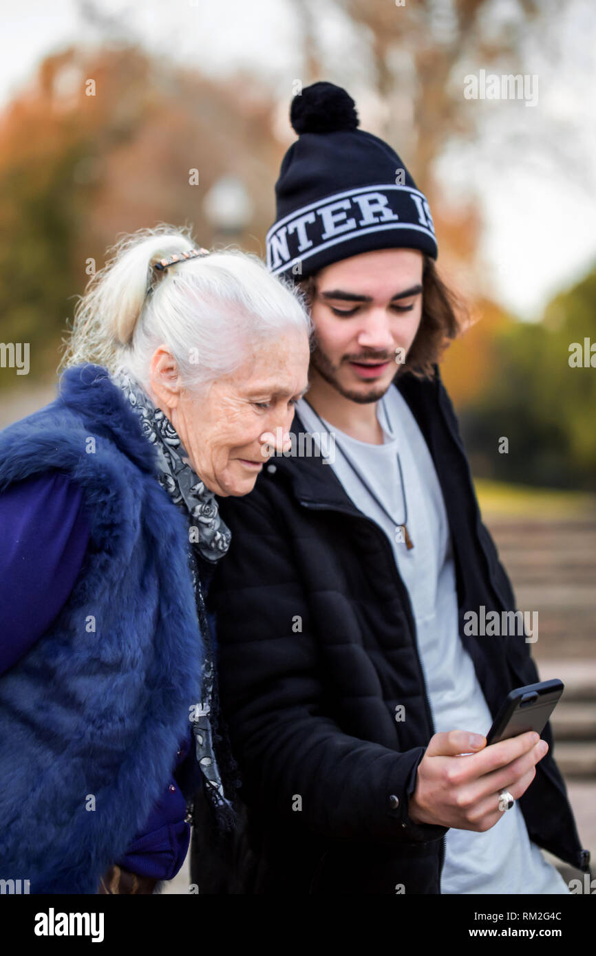 Piacevole giovane uomo mostra la sua nonna le foto su uno smartphone Foto Stock