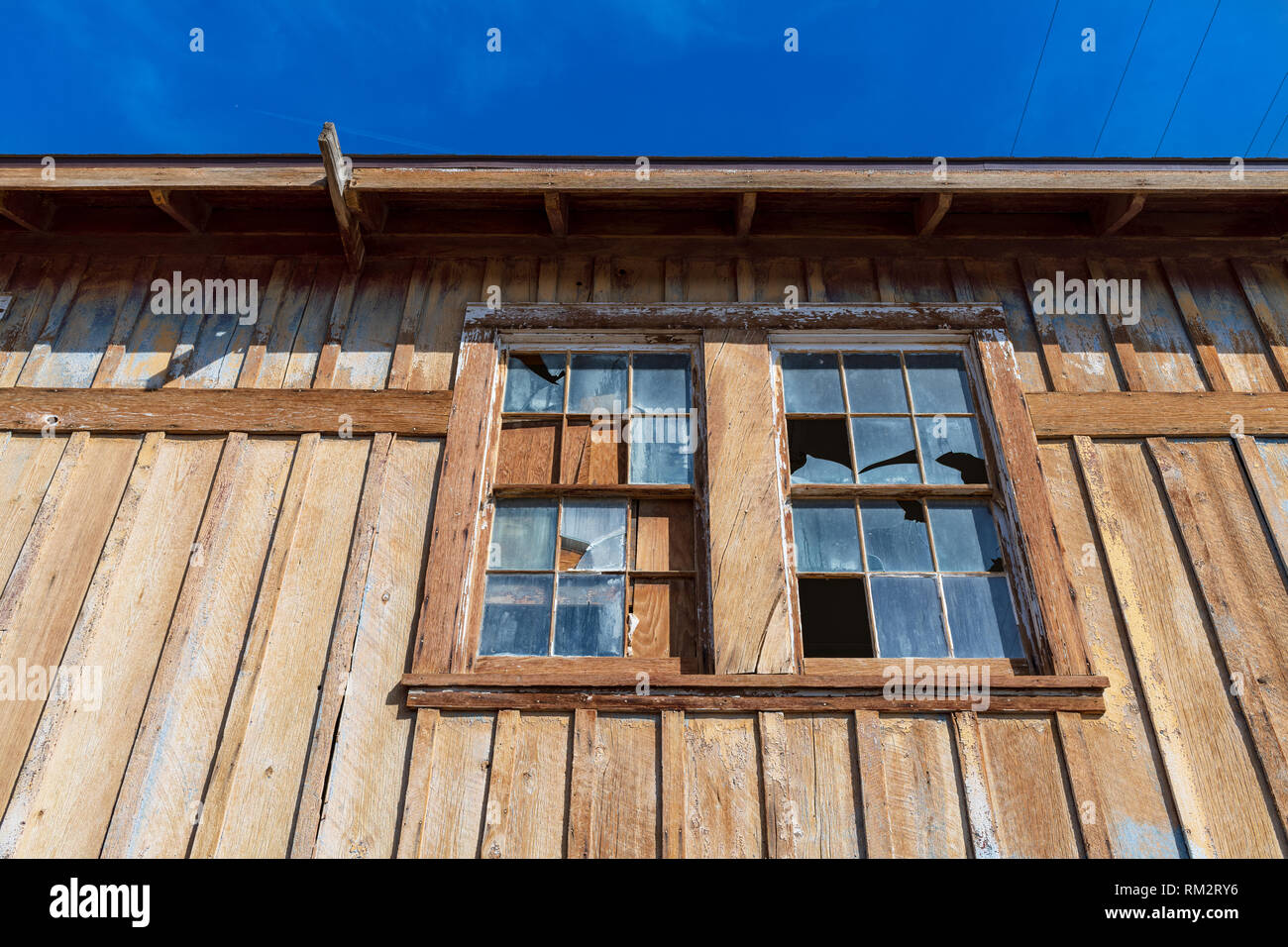 Vetri rotti su un edificio di legno con un cielo blu Foto Stock