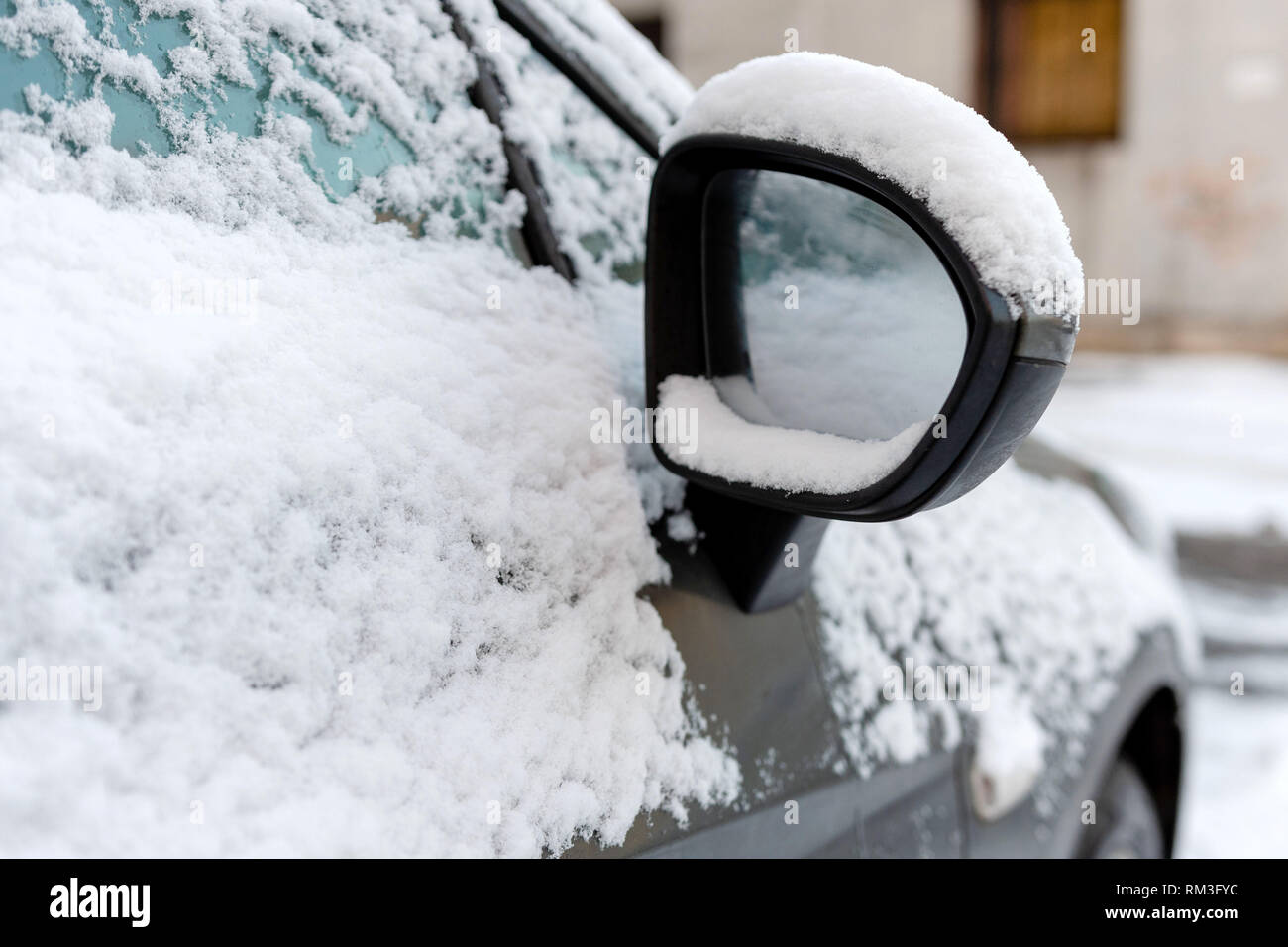 Close-up di coperta di neve auto specchio di ala. Foto Stock