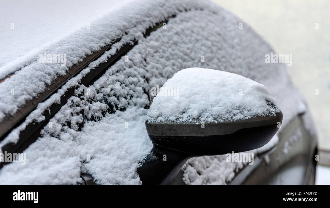 Close-up di coperta di neve auto specchio di ala. Foto Stock