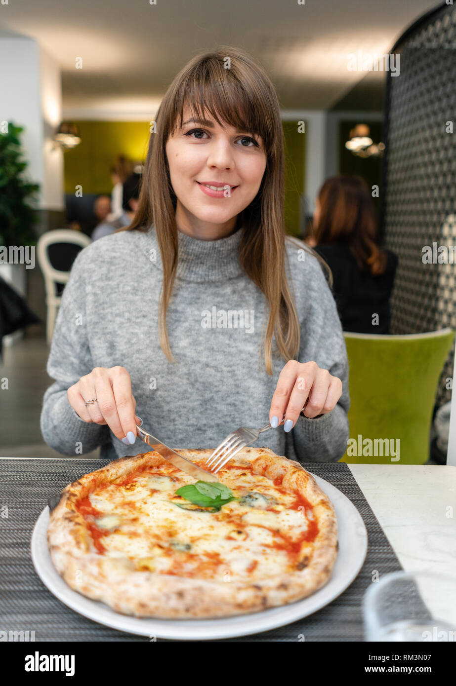 Donna mangia con coltello e forchetta una pizza Margherita con mozzarella  di bufala pomodori e basilico. Pizza Napoletana da stufa a legna. Pranzo in  un italiano Foto stock - Alamy