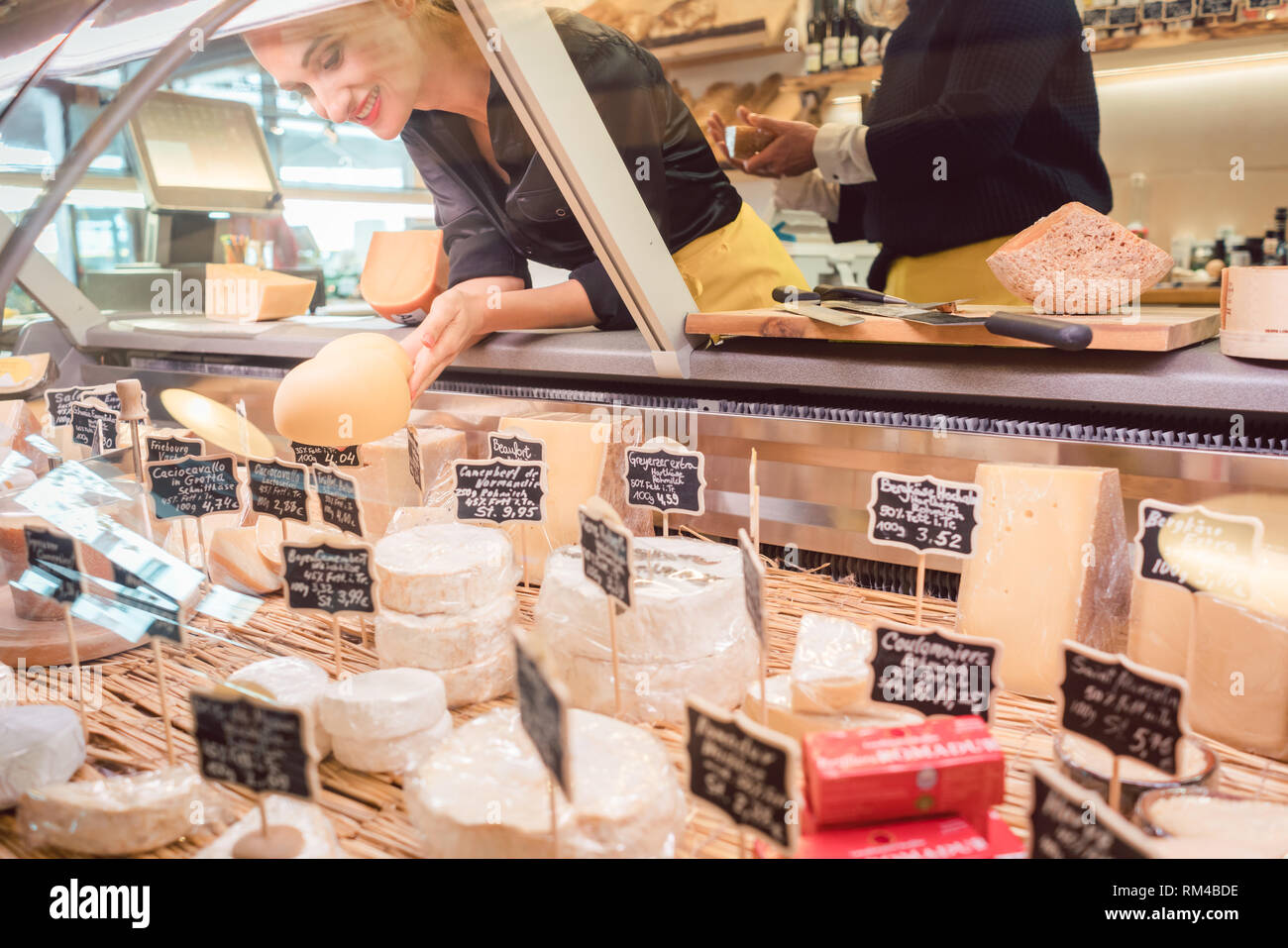 Commessa donna formaggio di smistamento nel supermercato display per venderlo Foto Stock