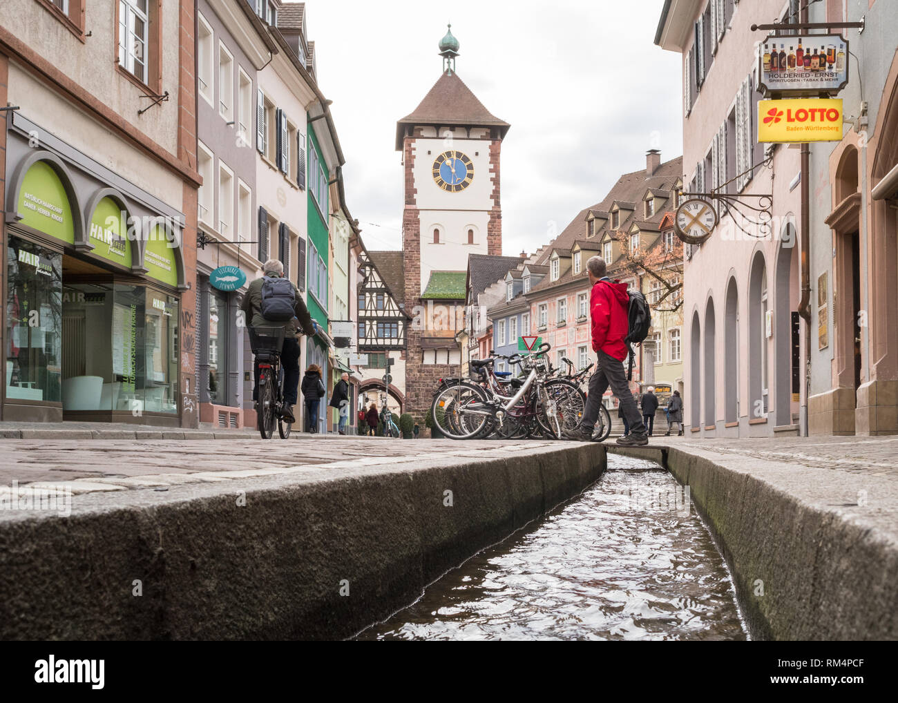 Freiburg im Breisgau - tourist attraversando un bachle - un'acqua riempito runnel - di fronte al Schwabentor (città sveva gate), Germania, Europa Foto Stock