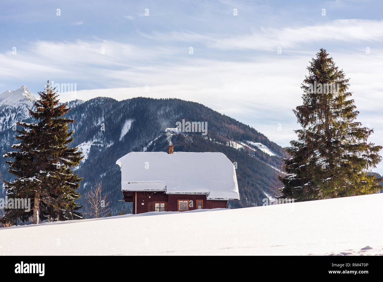 Casa di montagna e due alberi, montagne dalle vette innevate sullo sfondo nella regione sciistica di Schladming-Dachstein, Liezen District, Stiria, Austria, Europa Foto Stock