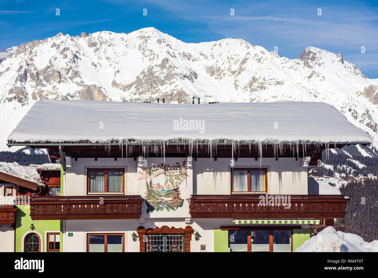 Casa di montagna con cime innevate sullo sfondo nella regione sciistica di Schladming-Dachstein, massiccio Dachstein, Liezen District, Stiria, Austria, Europa Foto Stock