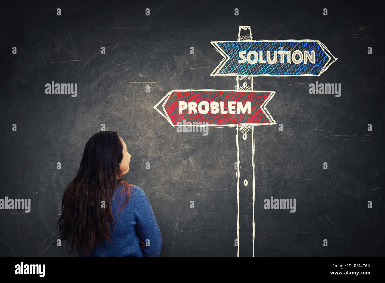 Vista posteriore della donna di fronte a blackboard guardando un cartello con le frecce che mostrano la soluzione e problema frecce ai lati destro e sinistro. Business directi Foto Stock