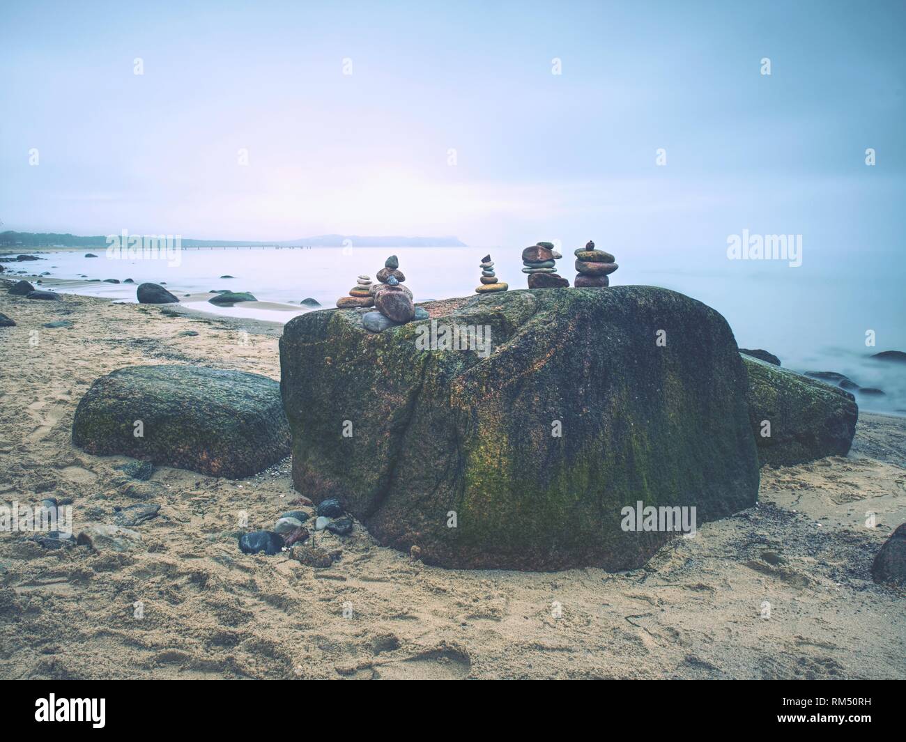 Piramide di pietre che simboleggia lo zen, armonia, equilibrio su sfondo oceano. Foto Stock