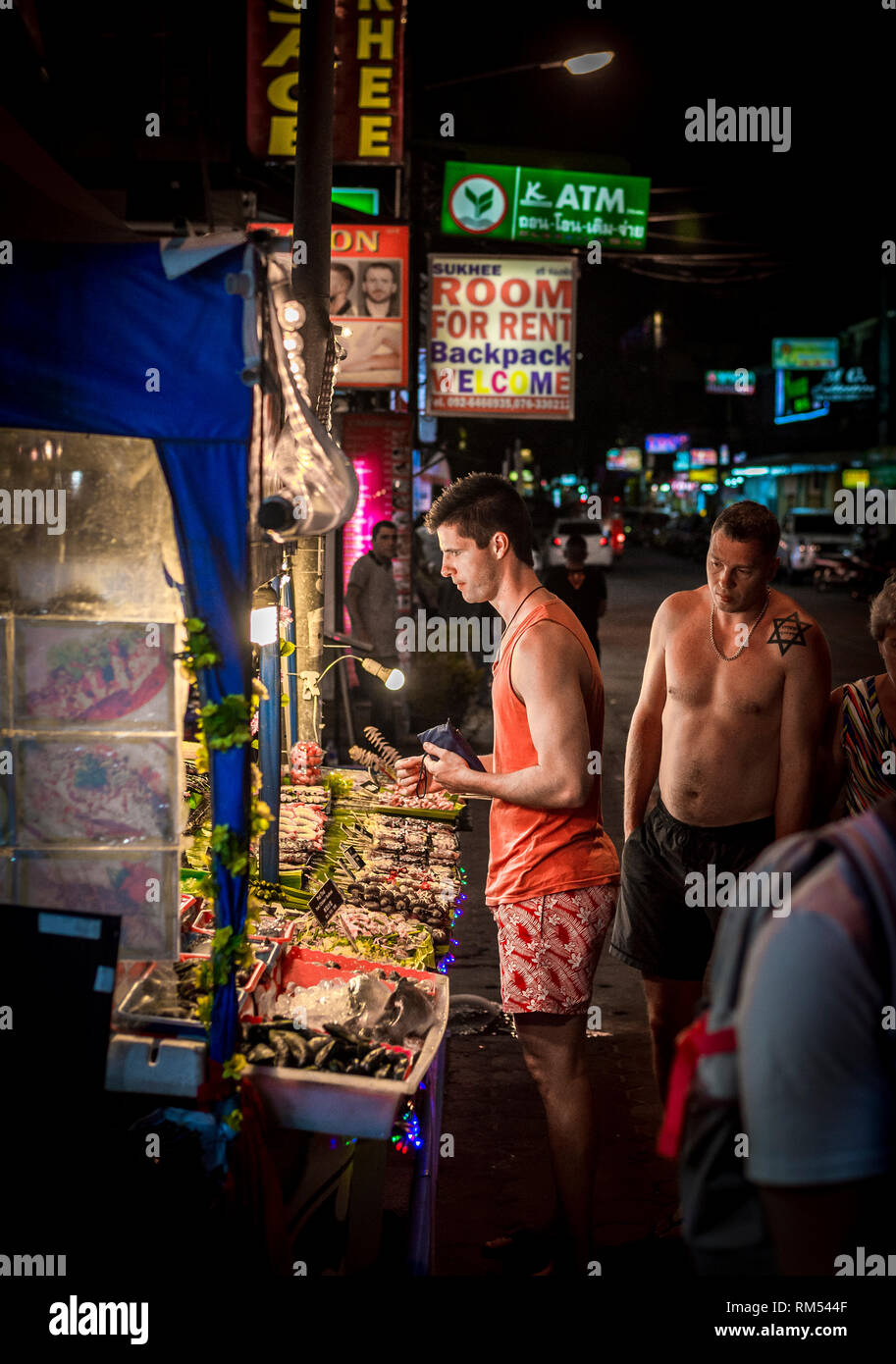 Turista che acquista cibo di strada da una bancarella in un mercato a Phuket, Thailandia. Foto Stock
