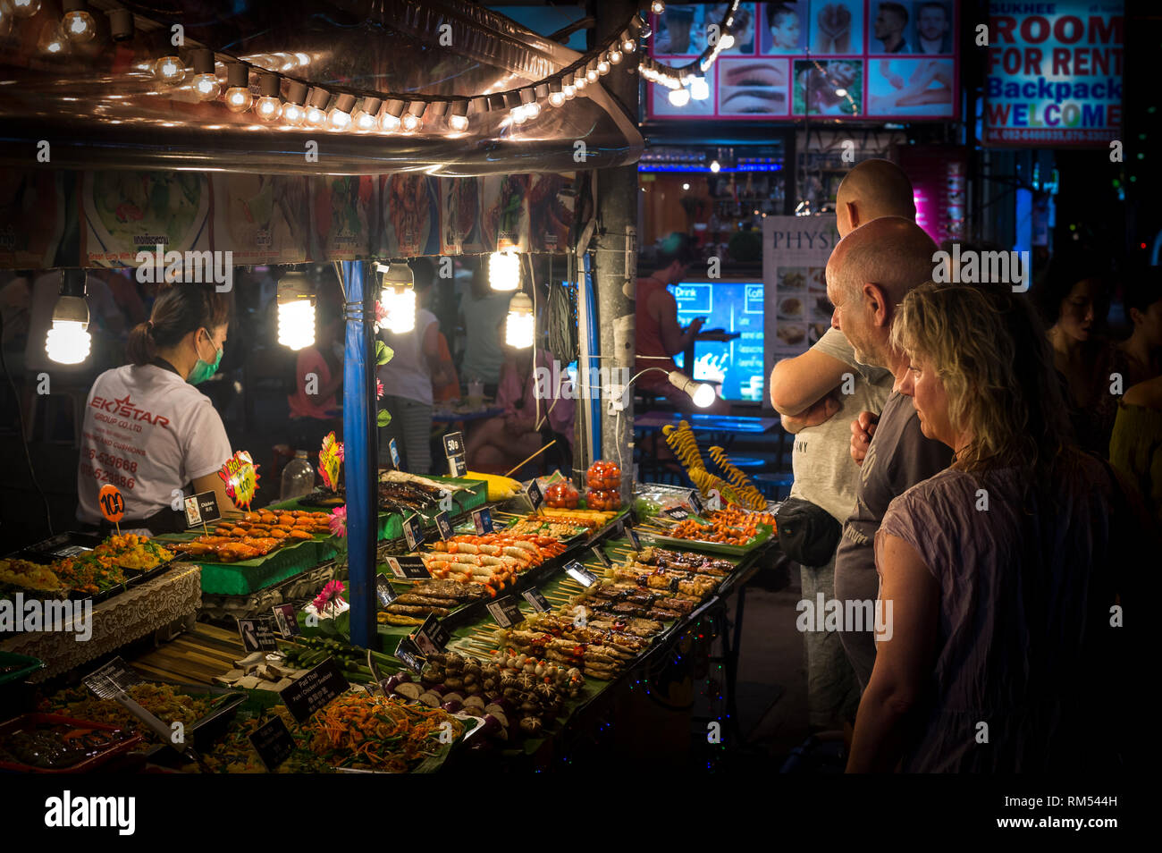 Turisti che acquistano cibo di strada da una bancarella in un mercato a Phuket, Thailandia. Foto Stock