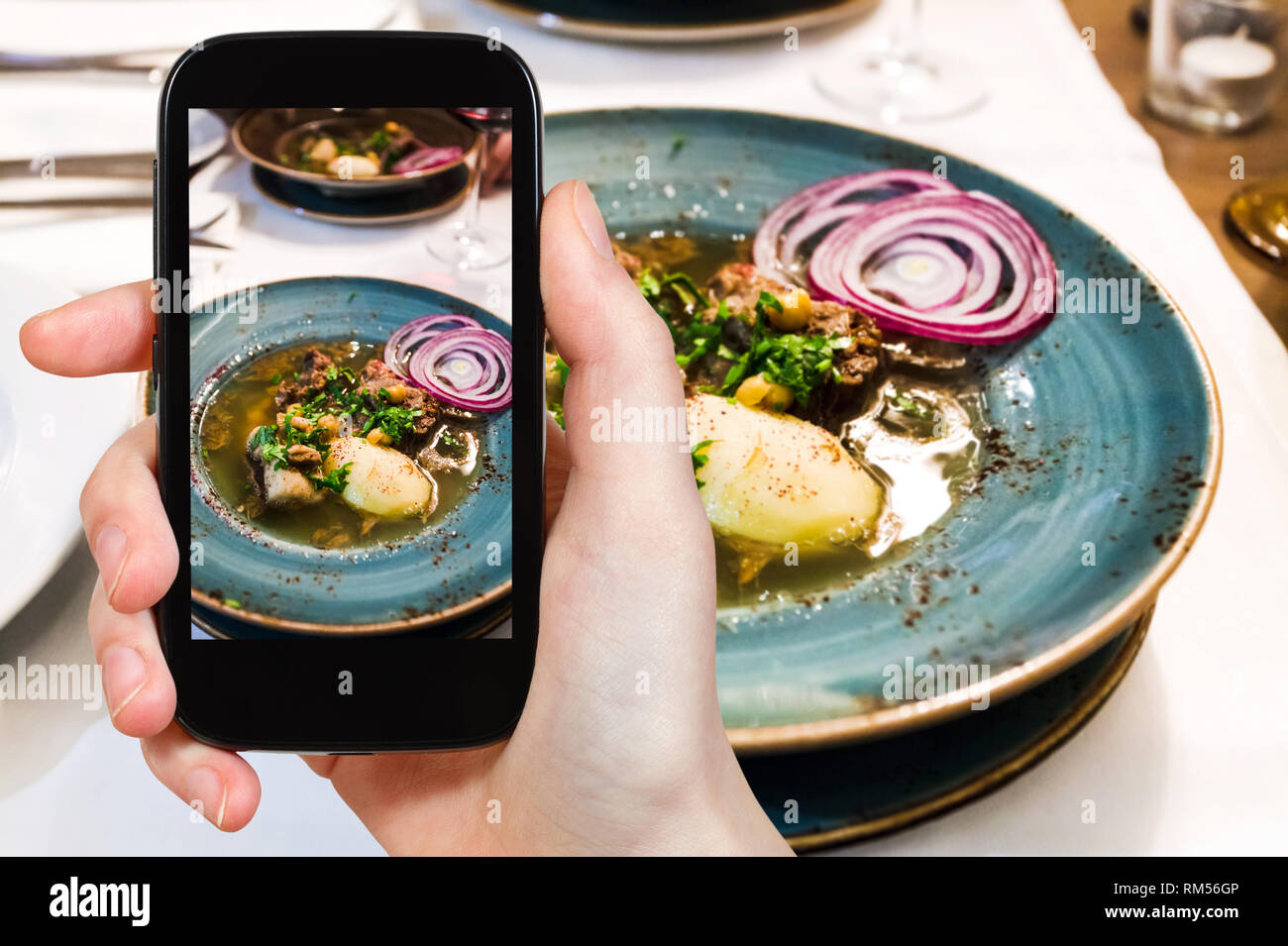 Concetto di viaggio - visitatore fotografie della tradizionale zuppa caucasica Putuk (Piti) da Montone punta di petto, ceci, patate nella piastra sullo smartphone Foto Stock