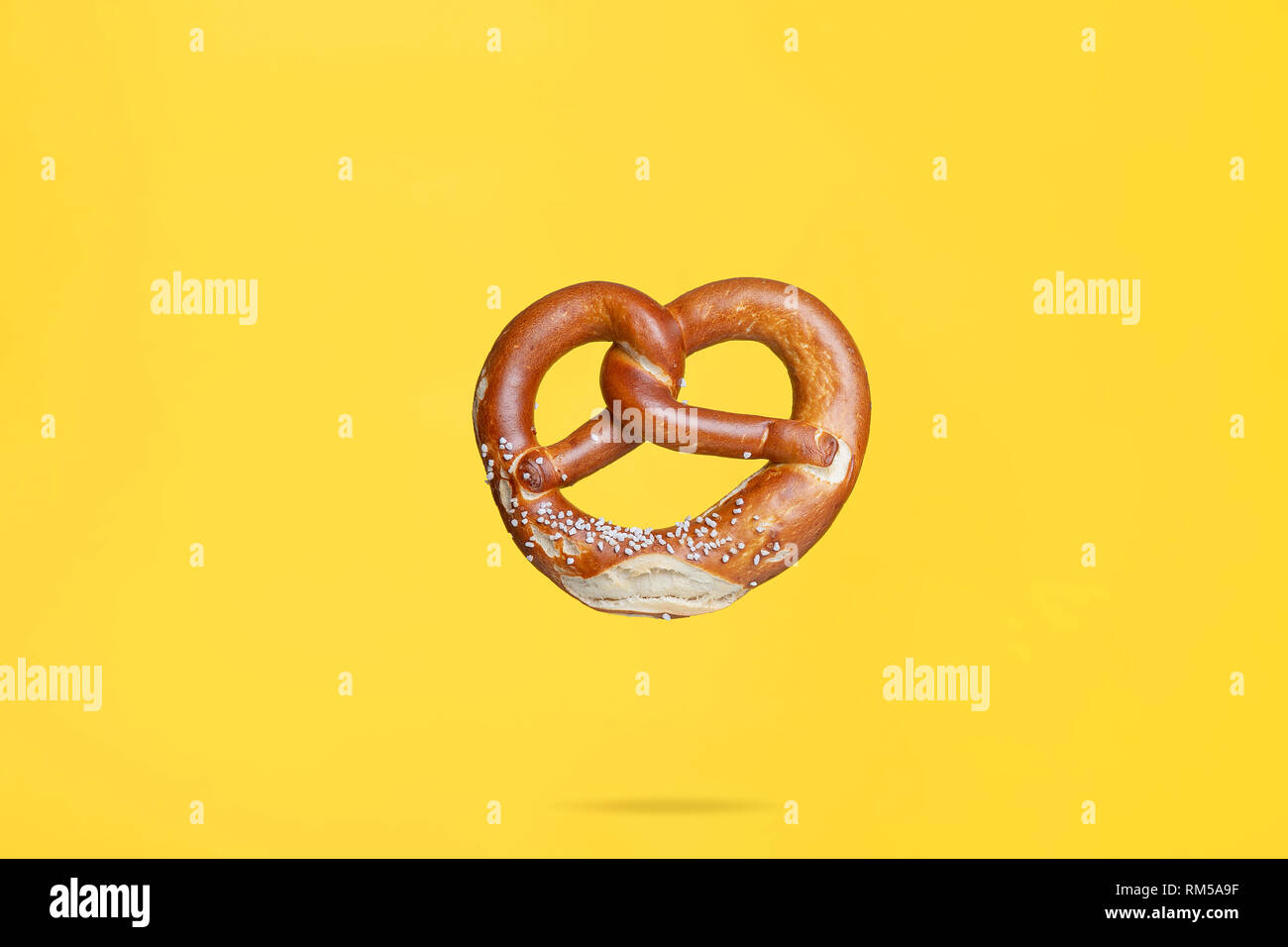 Flying panetteria alimentari concetto tradizionale tedesco salati pretzel su sfondo giallo Foto Stock