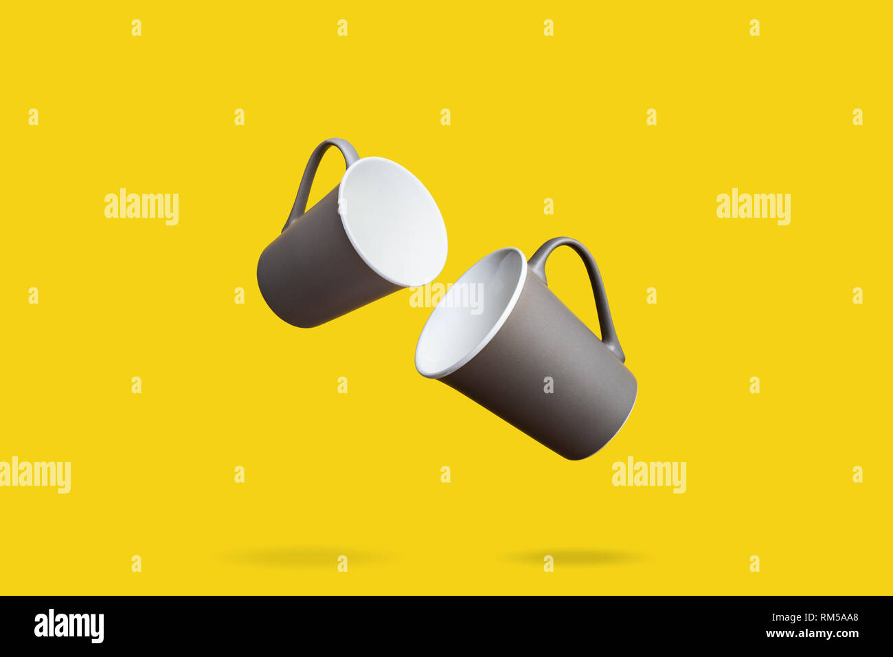 Concetto di volo Gruppo di colore marrone scuro Grigio caffè in porcellana TAZZE TÈ su sfondo giallo Foto Stock