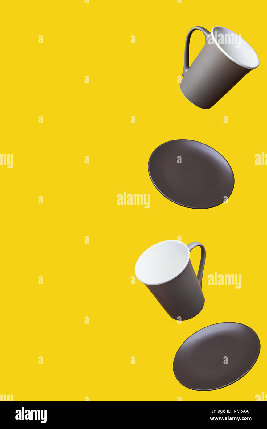 Concetto di volo Gruppo di colore marrone scuro Grigio PorcelainCoffee Tazza da tè e la piastra su sfondo giallo Foto Stock