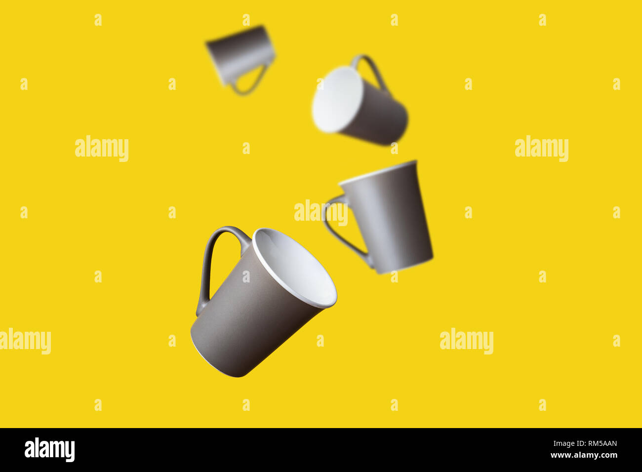 Concetto di volo Gruppo di colore marrone scuro Grigio caffè in porcellana Tazza da tè su sfondo giallo Foto Stock