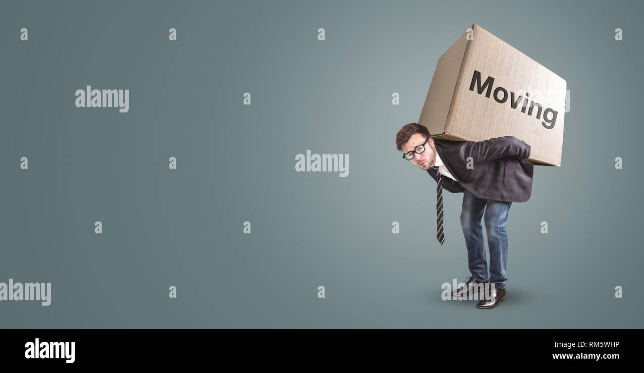 Un uomo è portatore di una grande scatola di cartone con la parola "in movimento" su di esso Foto Stock