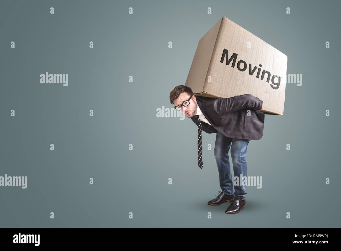 Un uomo è portatore di una grande scatola di cartone con la parola "in movimento" su di esso Foto Stock