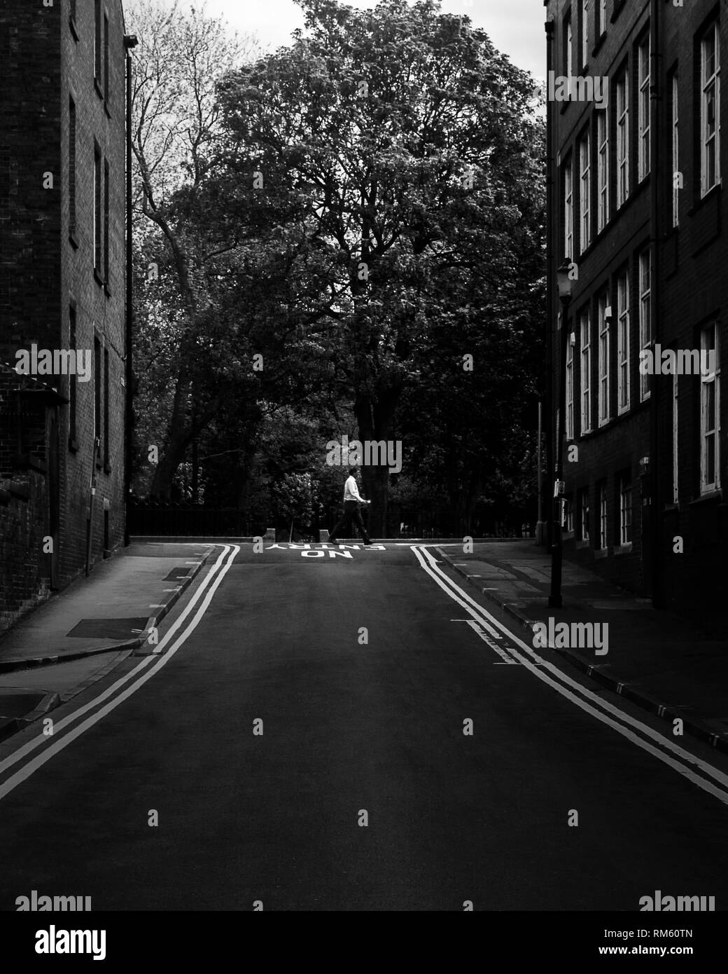 Un uomo attraversa la strada in distanza nel centro della citta' di Preston Foto Stock Un uomo attraversa la strada in distanza nel centro della citta' di Preston Foto Stock