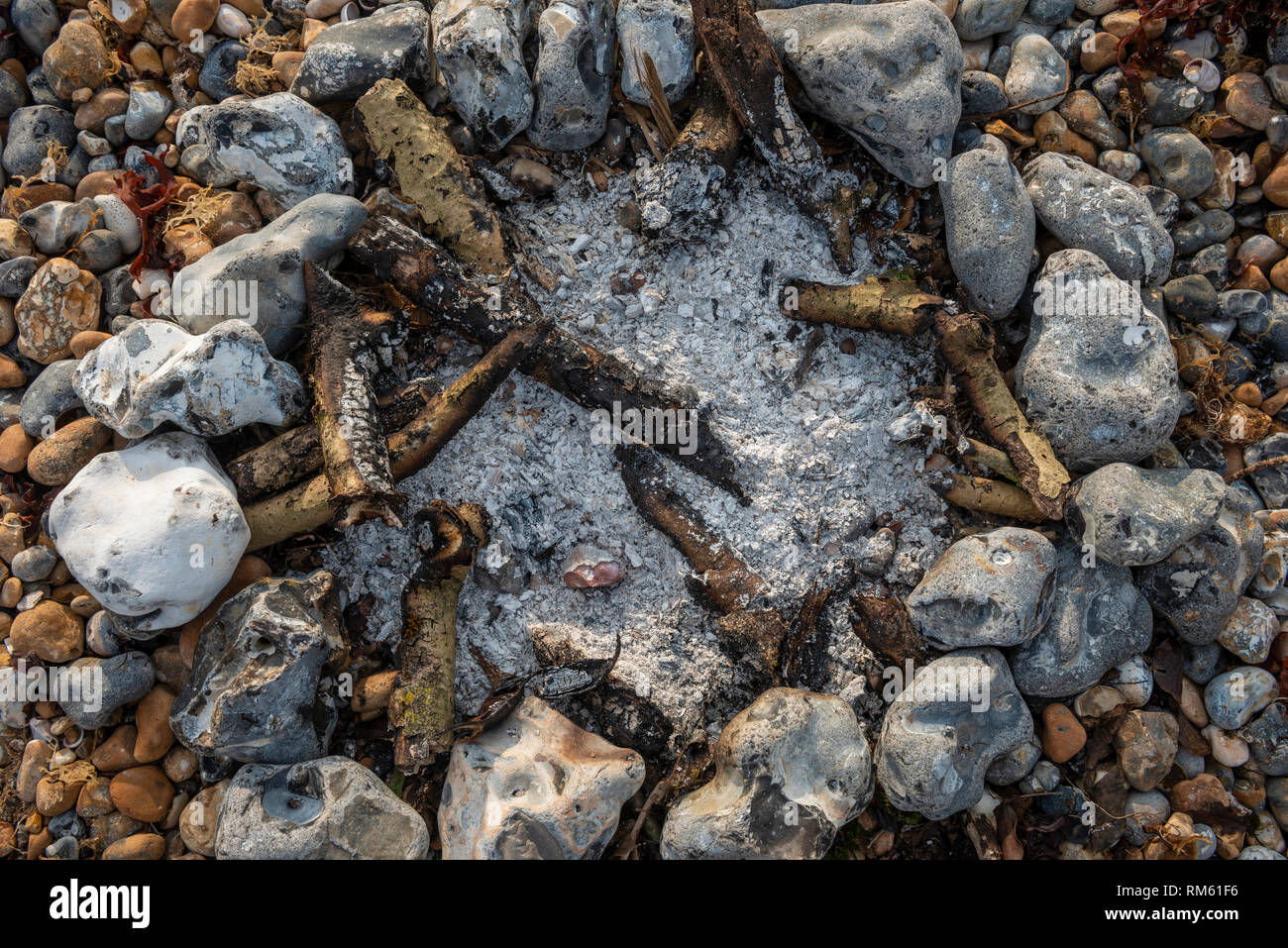 Resti di un incendio di piccole dimensioni su una spiaggia ghiaiosa Foto Stock