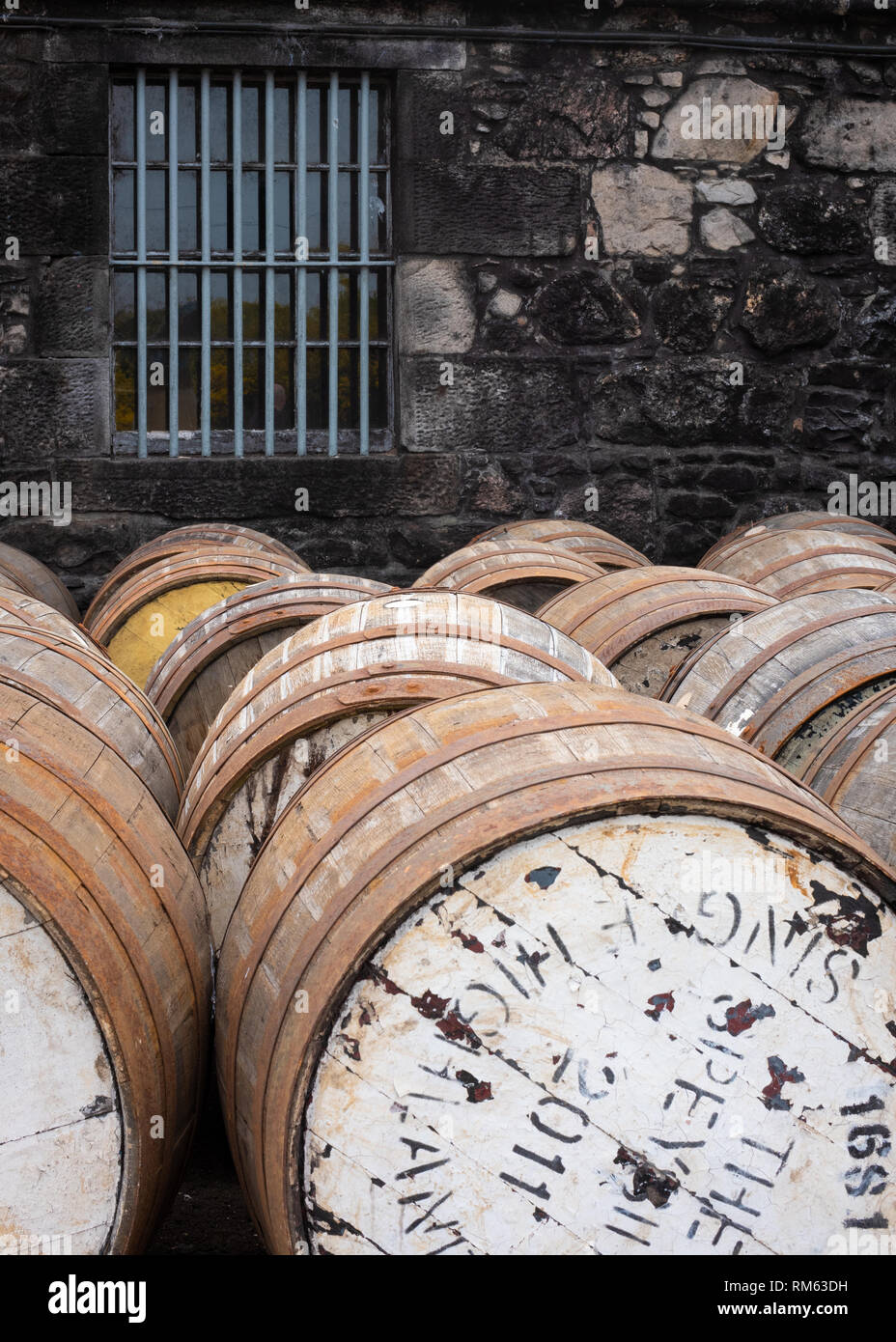 Vecchie botti di whisky schierate sul loro lato esterno vicino alla parete del Balblair distilleria di whisky in Scozia Foto Stock