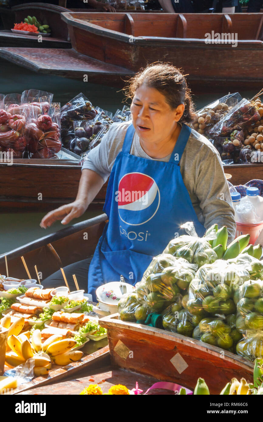 Damnoen Saduak, Tailandia - 4 Marzo 2017: fornitore di frutta pagaie la sua barca. Il mercato galleggiante è una meta turistica molto atrraction Foto Stock